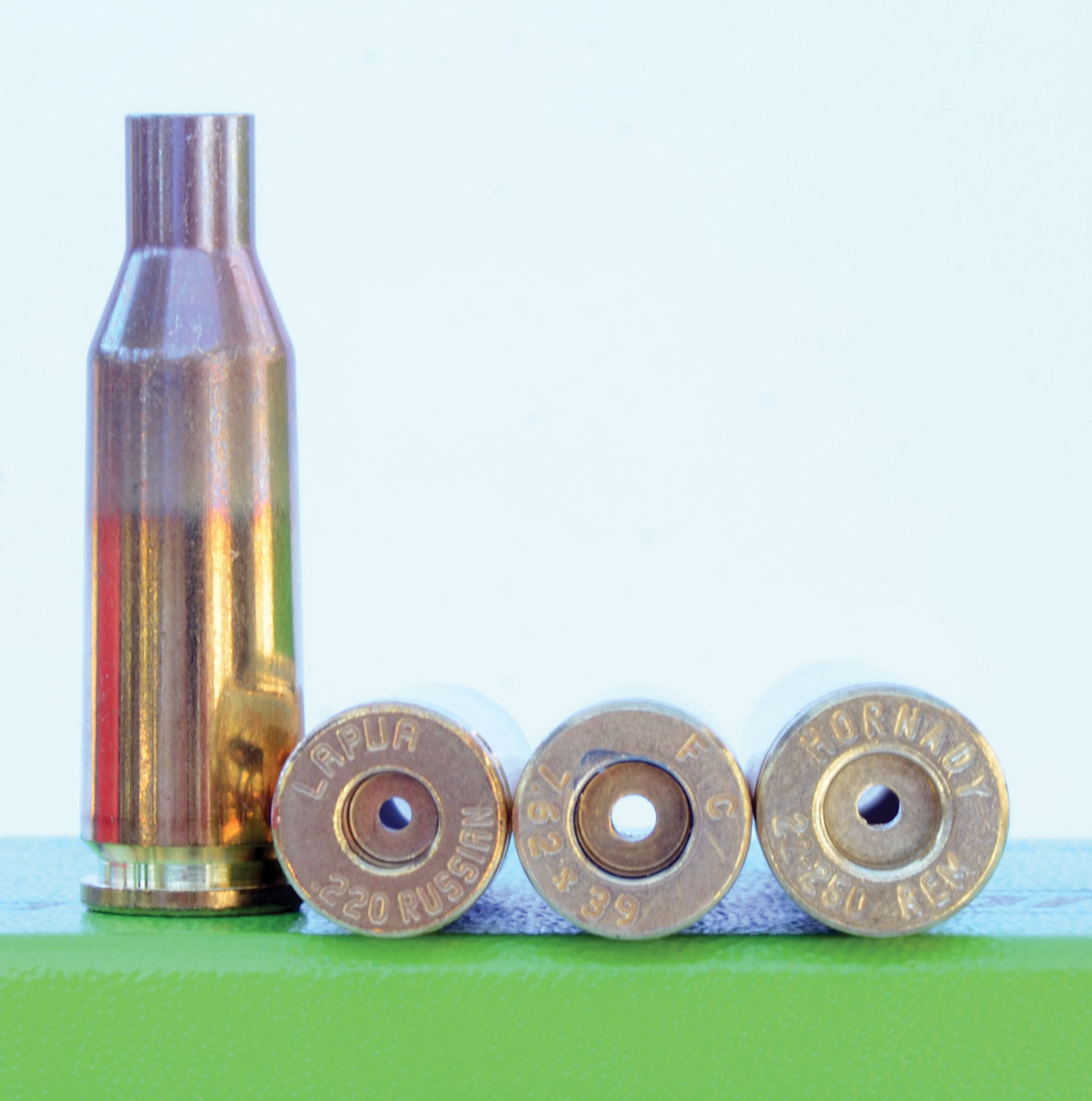 The use of small rifle primers and a flash hole of reduced diameter are considered to be important PPC design details. Pictured is a 22 PPC case formed from Lapua 220 Russian brass compared to a 7.62x39mm case (center) with a large rifle primer pocket and a flash hole of more standard diameter. Rim diameter (.273 inch) of the 22-250 case (right) is slightly larger.